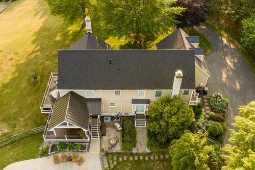 Aerial view of a farmhouse with twin chimneys, a gazebo-style porch and garden path