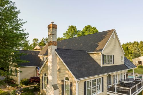 Aerial close-up of a farmhouse with stone chimney, deck and pool
