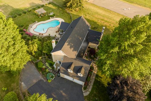 Aerial view of a farmhouse with pool, pergola and a grass airstrip in the distance