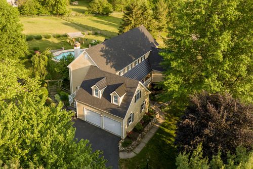 Aerial view of a farmhouse with pool, stone patio and fenced pasture beyond