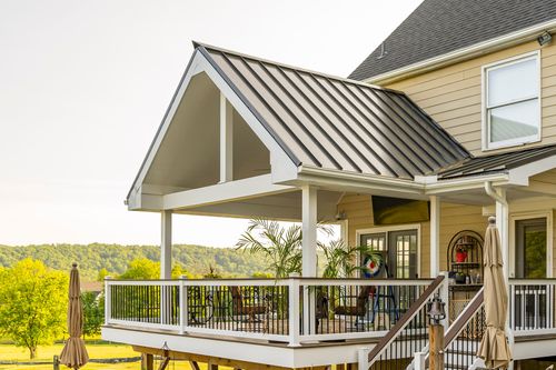Covered deck with rocking chairs, a standing-seam roof and rolling hills in the distance