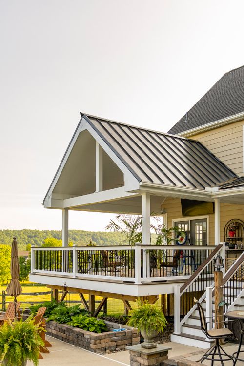 Covered deck with rocking chairs, string lights and raised garden beds