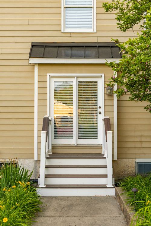 Rear entrance with a metal-roofed awning, French door and wood deck stairs
