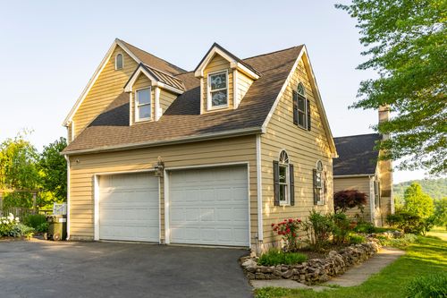 Two-car garage with matching gable dormers above on a shingle-roofed exterior