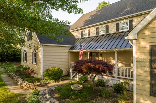 Front porch with an American flag, Japanese maple tree and white railings