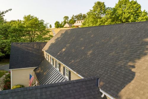 Close-up of a dark standing-seam metal roof against a farmhouse dormer