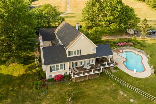 Aerial view of a farmhouse rear yard with a covered deck, pool and patio furniture